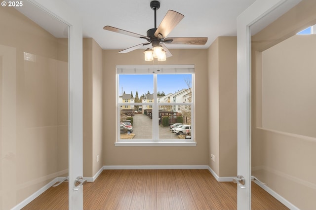 unfurnished dining area with ceiling fan, wood finished floors, and baseboards