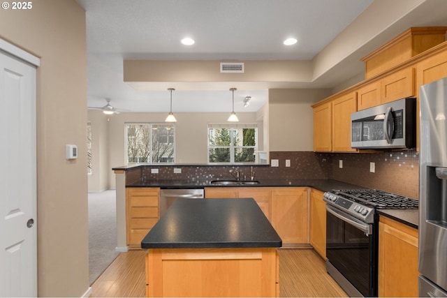 kitchen with visible vents, dark countertops, appliances with stainless steel finishes, a peninsula, and a sink