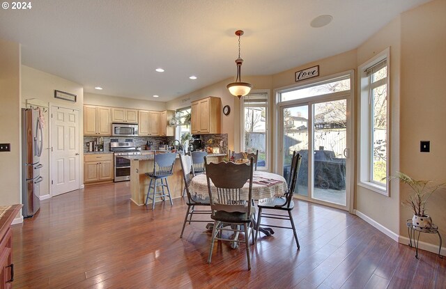 kitchen with sink, tasteful backsplash, dark stone countertops, hardwood / wood-style floors, and appliances with stainless steel finishes