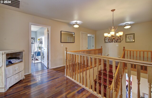 hallway with a textured ceiling, an inviting chandelier, and dark wood-type flooring