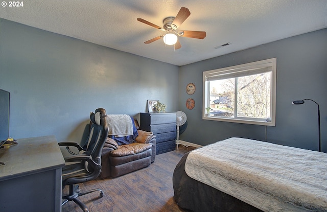 bedroom featuring ceiling fan, dark hardwood / wood-style flooring, and a textured ceiling