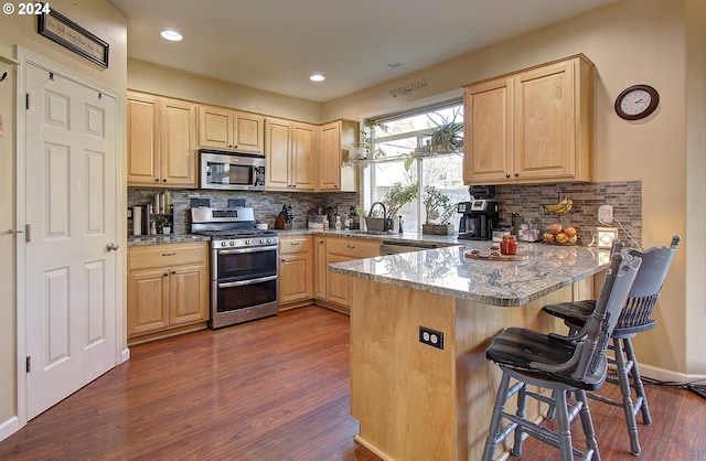 kitchen featuring kitchen peninsula, light brown cabinetry, and stainless steel appliances