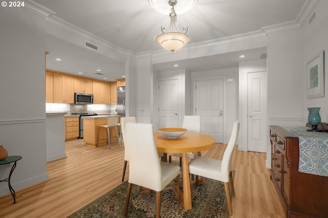 dining area with crown molding and light hardwood / wood-style floors