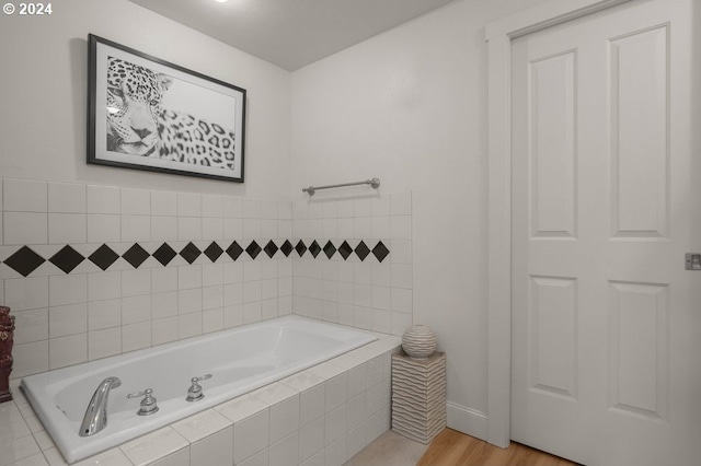 bathroom with hardwood / wood-style flooring and a relaxing tiled tub