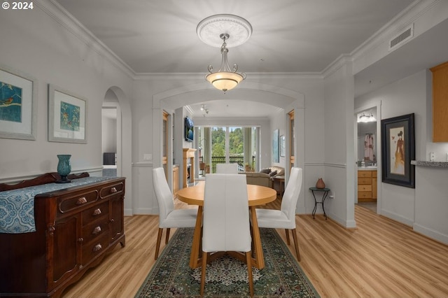 dining space featuring light wood-type flooring and crown molding