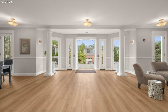 interior space with light hardwood / wood-style flooring, ornate columns, and a wealth of natural light