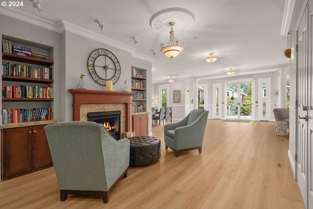 living room with light hardwood / wood-style flooring, built in features, decorative columns, and crown molding