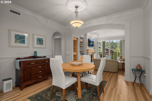 dining space featuring built in shelves, light hardwood / wood-style floors, and crown molding