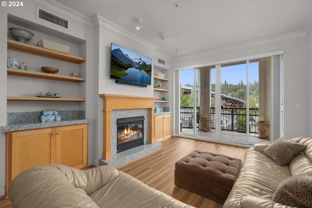 living room featuring ornamental molding, light wood-type flooring, and built in features