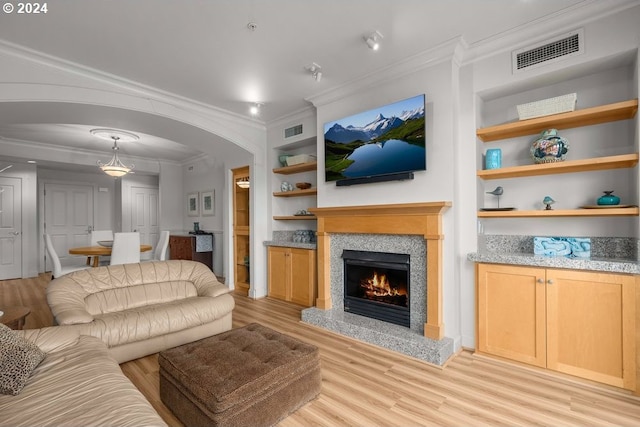 living room with ornamental molding, built in shelves, and light hardwood / wood-style floors