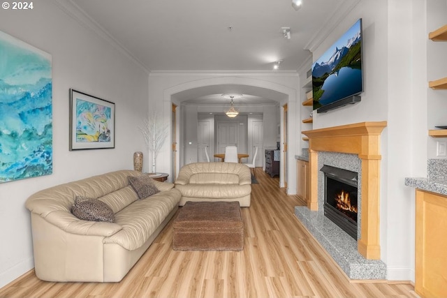 living room with light wood-type flooring, ornamental molding, and a tile fireplace