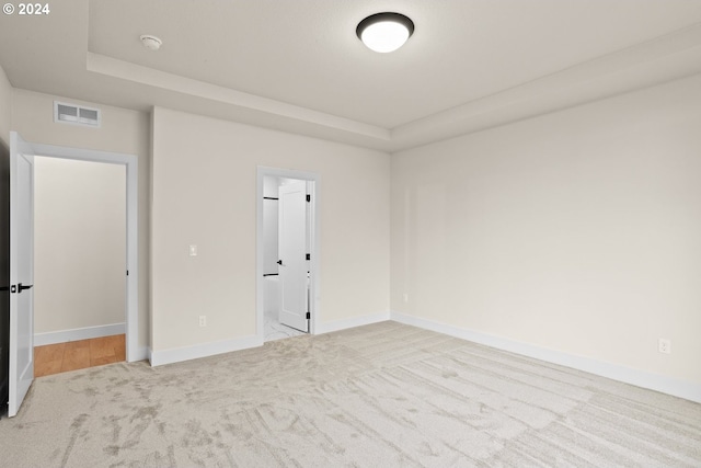 empty room with a tray ceiling and light colored carpet