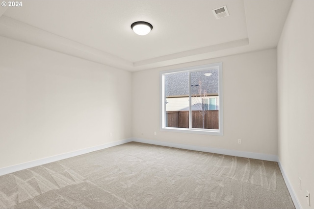 carpeted empty room with a tray ceiling