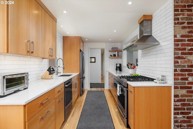 kitchen with wall chimney exhaust hood, a sink, stainless steel appliances, light wood-style flooring, and a toaster