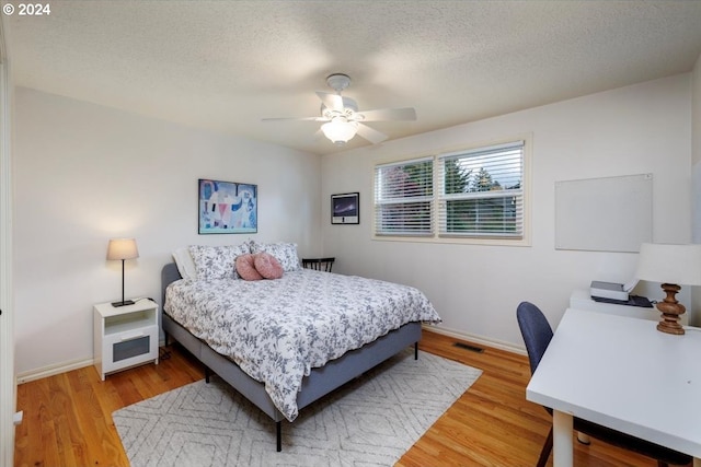 bedroom with light wood-type flooring, ceiling fan, baseboards, and visible vents