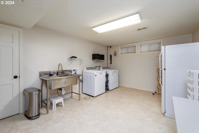 clothes washing area with washer and dryer, visible vents, laundry area, and a sink