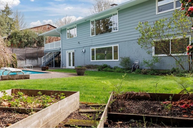 rear view of property with stairs, a garden, french doors, and a yard