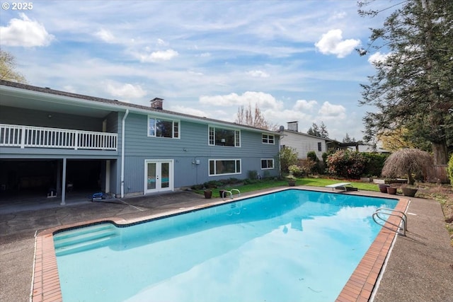 pool with a patio area, french doors, and a diving board