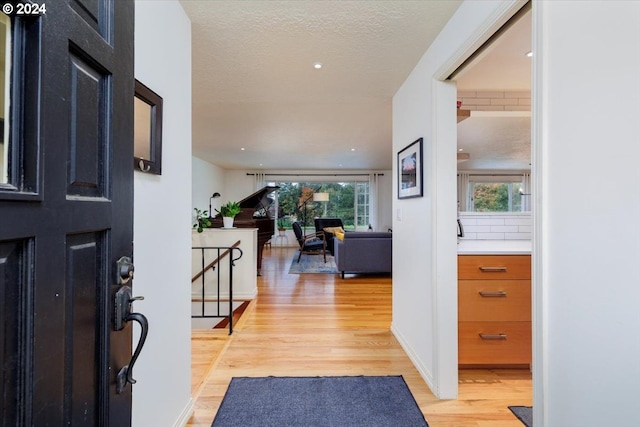foyer featuring light wood finished floors and a textured ceiling