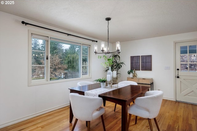 dining area with light wood-style flooring, a chandelier, baseboards, and a textured ceiling
