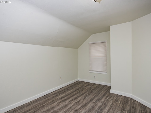 additional living space featuring vaulted ceiling and dark wood-type flooring