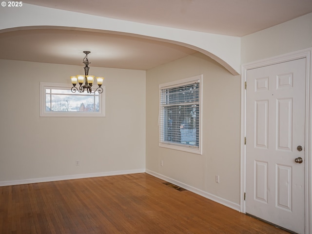 unfurnished room with hardwood / wood-style floors and a chandelier