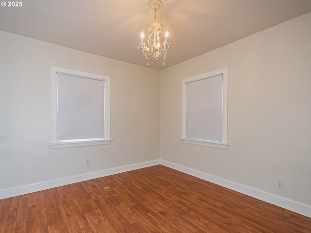 spare room with hardwood / wood-style flooring and a notable chandelier