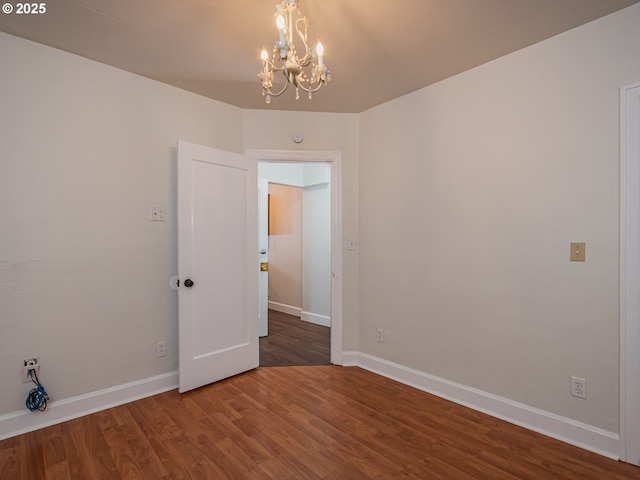 empty room featuring dark hardwood / wood-style flooring and a notable chandelier