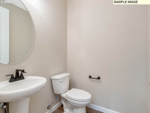 bathroom with a sink, baseboards, toilet, and wood finished floors