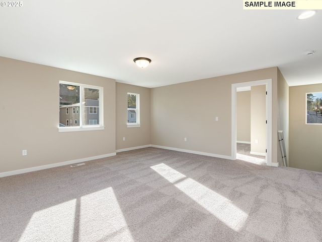 spare room featuring visible vents, carpet, and baseboards