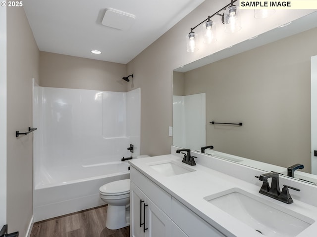 full bathroom featuring toilet, wood finished floors, and a sink