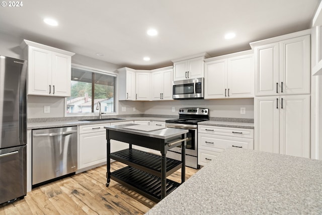 kitchen with white cabinets, stainless steel appliances, light hardwood / wood-style floors, and sink