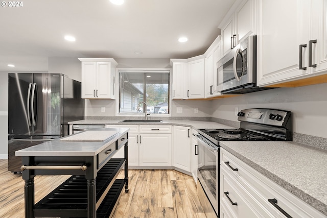 kitchen featuring sink, white cabinets, stainless steel appliances, and light hardwood / wood-style floors