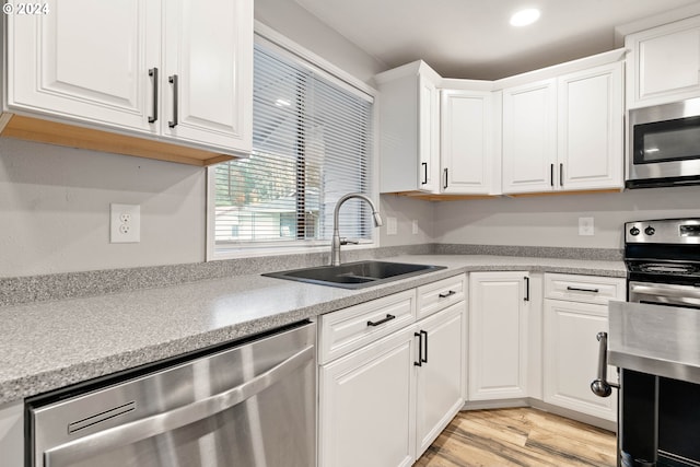 kitchen featuring white cabinets, sink, appliances with stainless steel finishes, and light hardwood / wood-style flooring