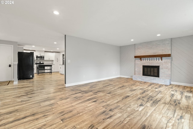 unfurnished living room with a fireplace and light wood-type flooring