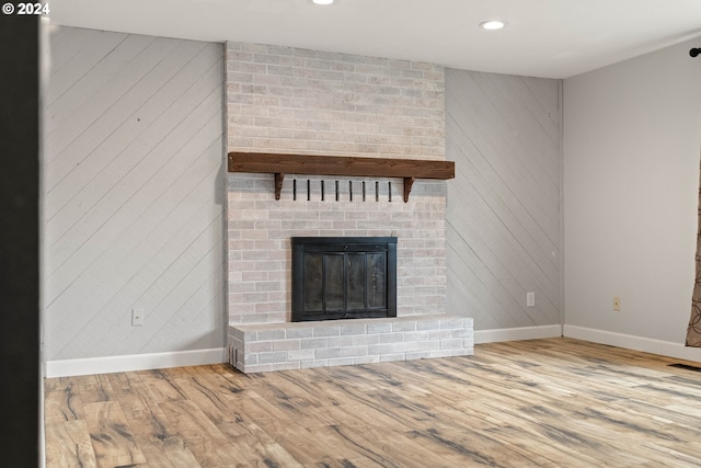 unfurnished living room with hardwood / wood-style flooring and a brick fireplace