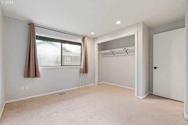 unfurnished bedroom featuring light colored carpet and a closet