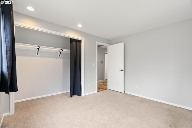 unfurnished bedroom with a closet and light colored carpet