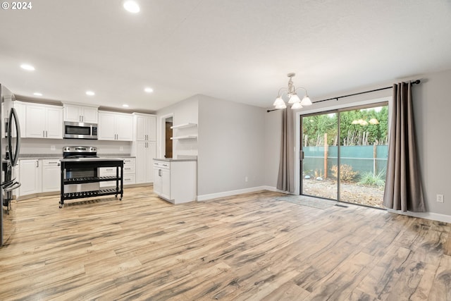 kitchen featuring appliances with stainless steel finishes, light wood-type flooring, decorative light fixtures, and white cabinetry