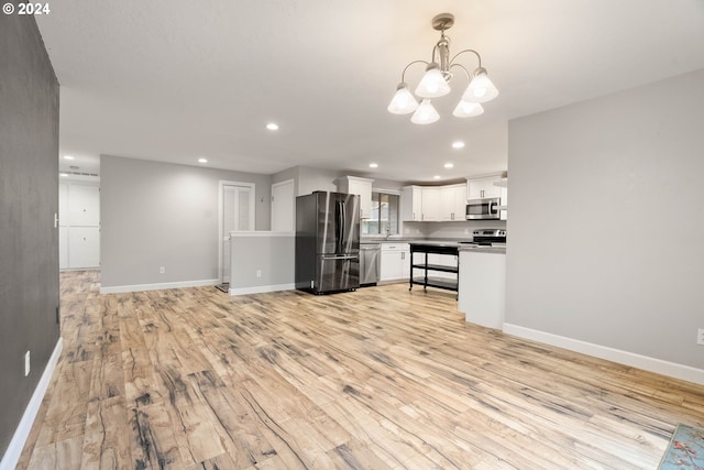 kitchen with an inviting chandelier, white cabinets, light hardwood / wood-style flooring, decorative light fixtures, and stainless steel appliances