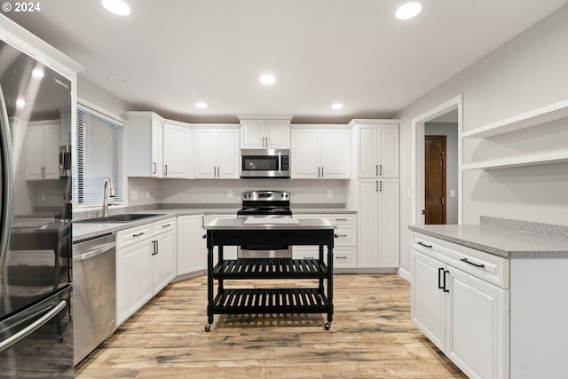 kitchen featuring appliances with stainless steel finishes, light wood-type flooring, white cabinetry, and sink