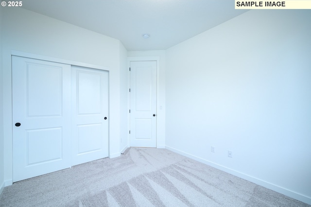 unfurnished bedroom featuring light colored carpet and a closet