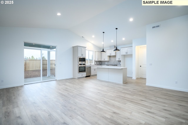 kitchen with a center island, hanging light fixtures, light hardwood / wood-style flooring, vaulted ceiling, and stainless steel appliances