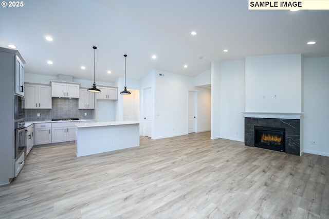 kitchen with tasteful backsplash, stainless steel appliances, a fireplace, a center island, and hanging light fixtures