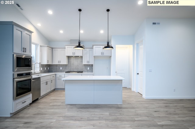 kitchen featuring a center island, hanging light fixtures, sink, appliances with stainless steel finishes, and tasteful backsplash