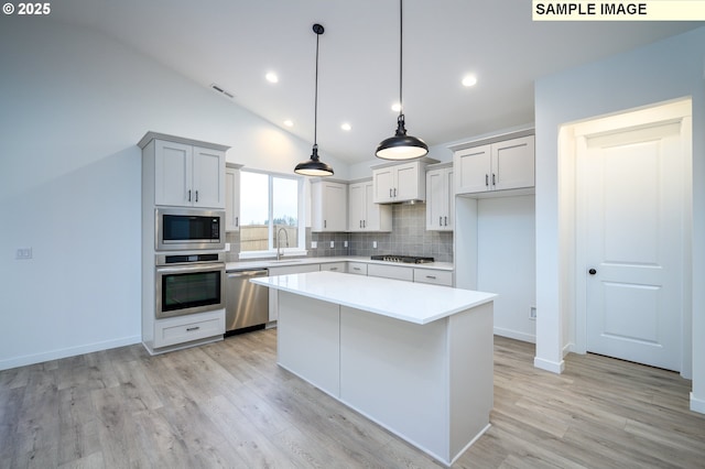 kitchen with decorative backsplash, appliances with stainless steel finishes, vaulted ceiling, sink, and a center island