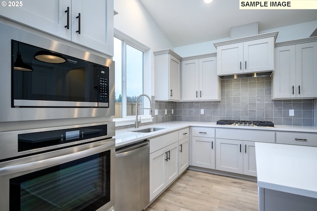 kitchen featuring white cabinets, sink, appliances with stainless steel finishes, tasteful backsplash, and light hardwood / wood-style floors