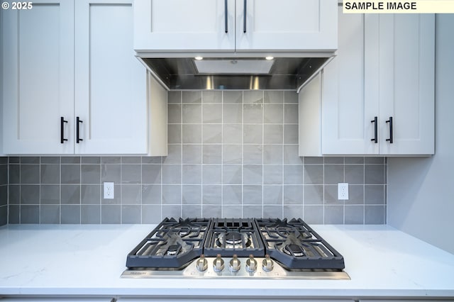 kitchen featuring light stone countertops, tasteful backsplash, stainless steel gas cooktop, and wall chimney exhaust hood