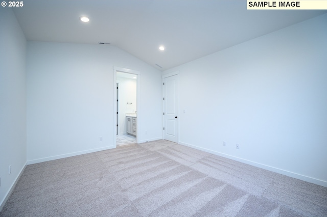 carpeted spare room with vaulted ceiling