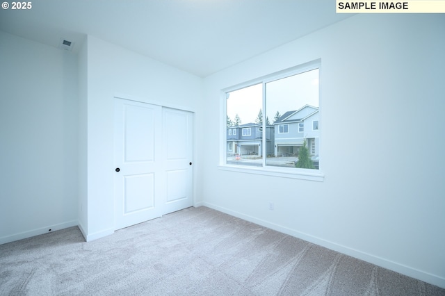 unfurnished bedroom with light carpet and a closet